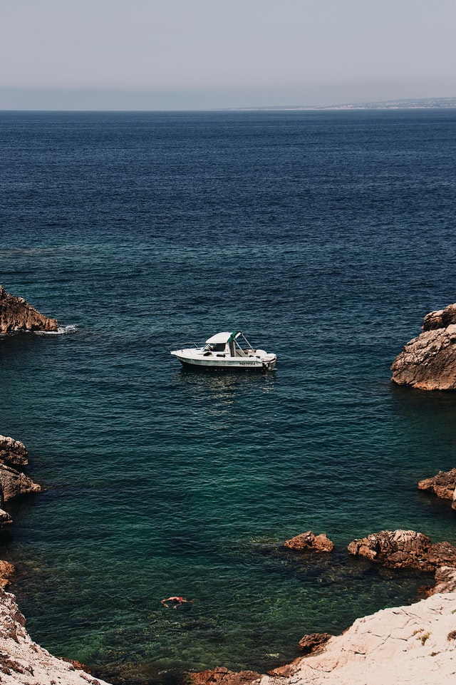 Vue d'un bateau sur la mer méditerranée entouré par des rochers
