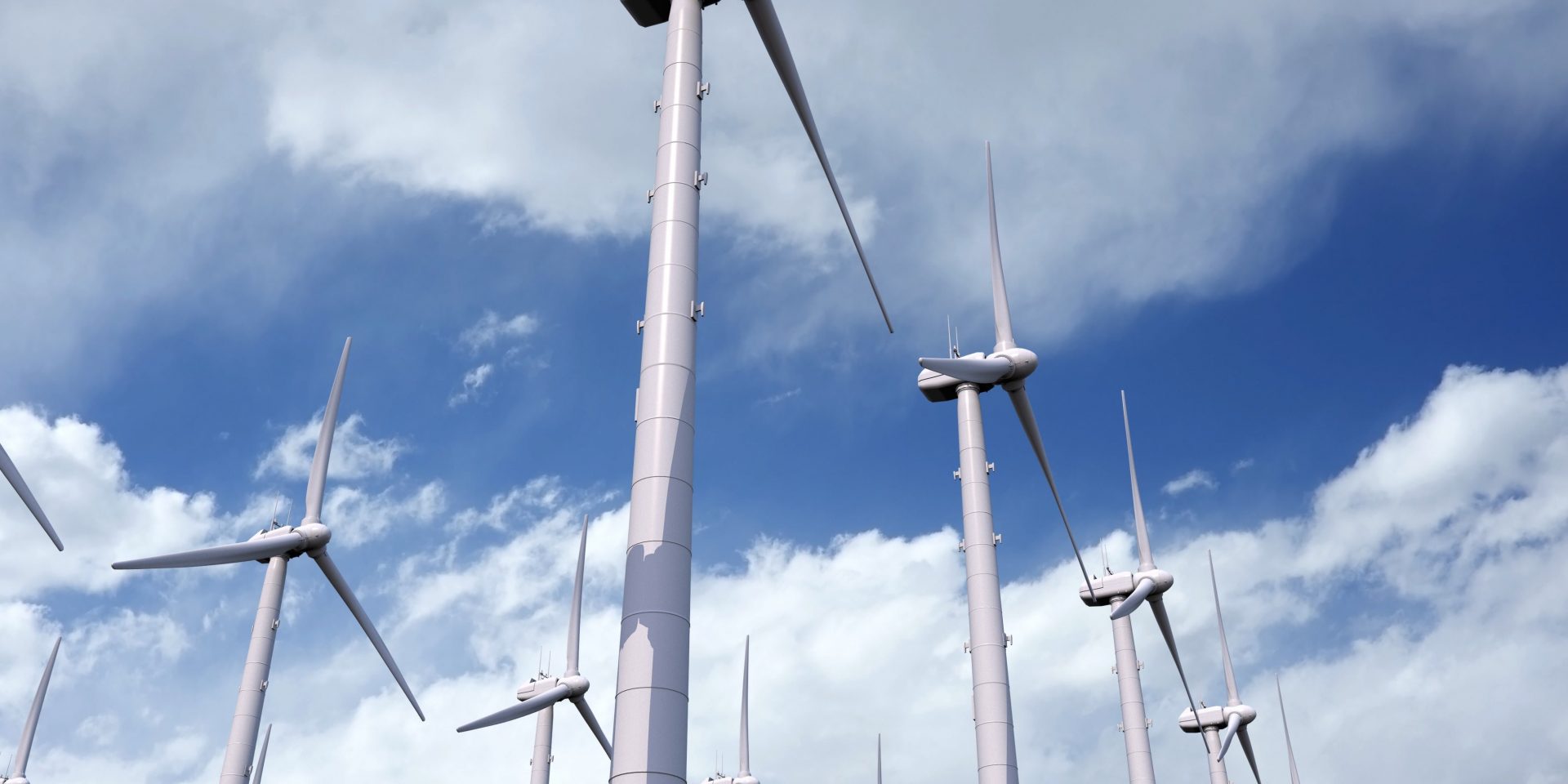 Vue du dessous de plusieurs éoliennes sous un ciel bleu nuageux